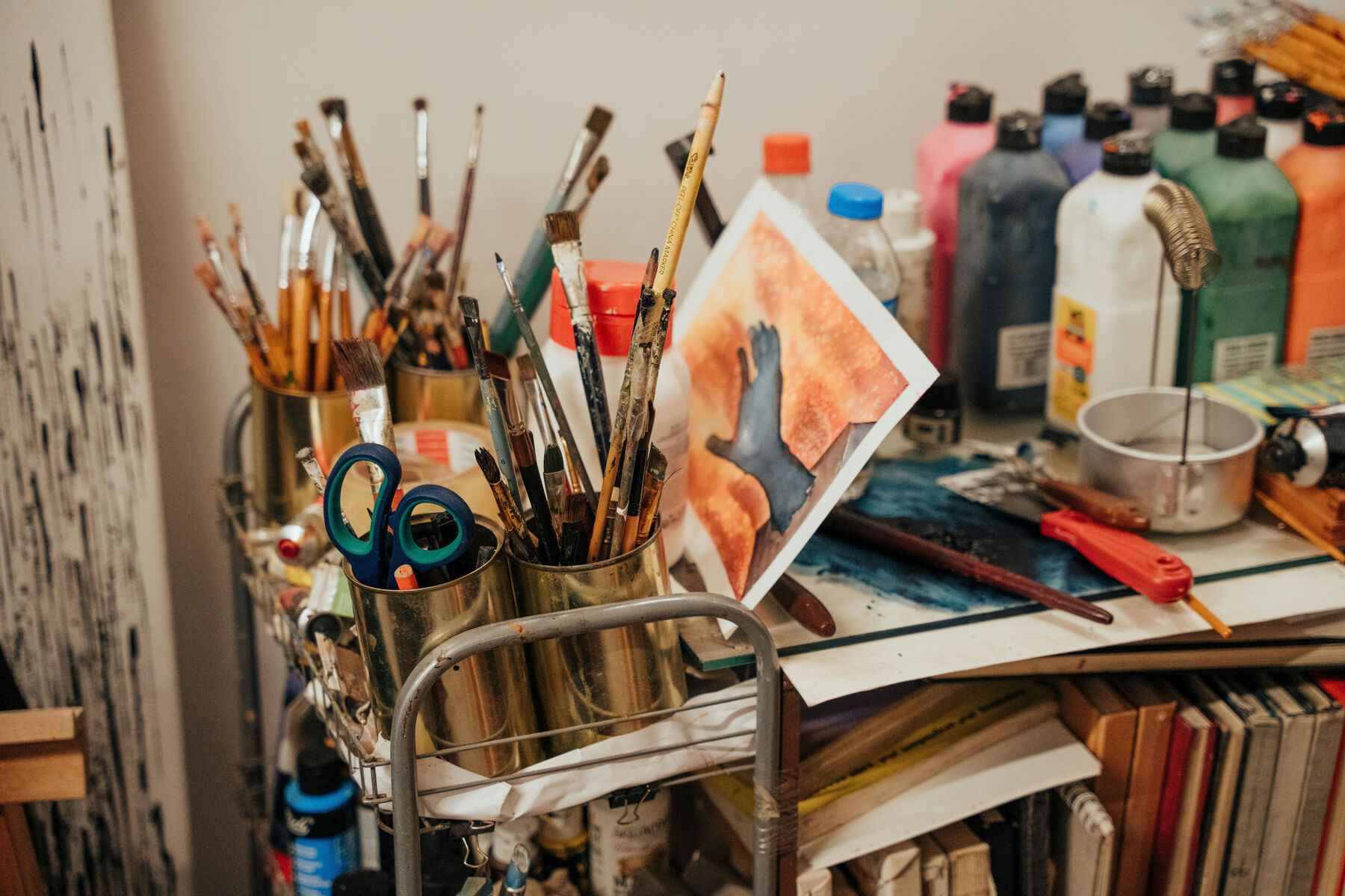 Brushes, paint and tools on a crowded studio trolley